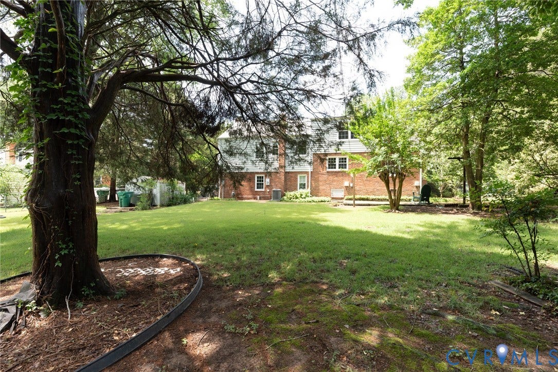 2519 Woodmont Drive, Woodmont, Chesterfield, VA 23235 Expansive backyard featuring a manicured lawn, mature trees, and a brick exterior dwelling
