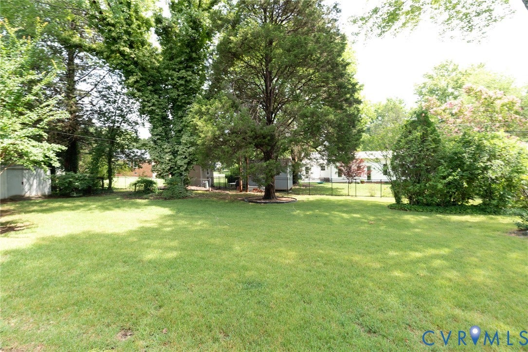2519 Woodmont Drive, Woodmont, Chesterfield, VA 23235 Expansive green lawn surrounded by mature trees, shrubbery, and a black wire fence
