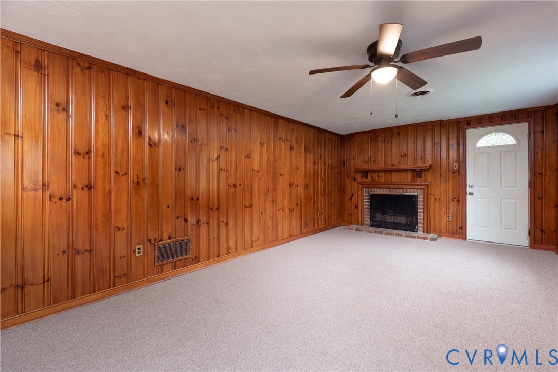 2519 Woodmont Drive, Woodmont, Chesterfield, VA 23235 Interior space featuring wood paneling, a brick fireplace with a wood mantel, a white door with an arched glass insert, a ceiling fan with integrated lighting, and light-colored carpeting