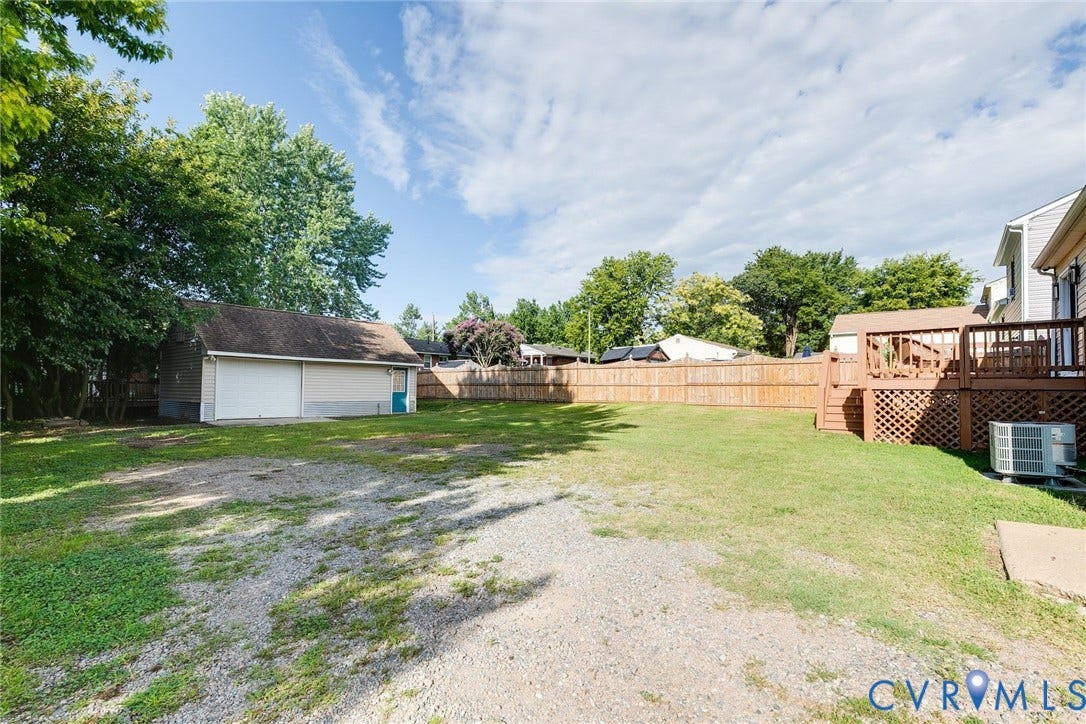 Huge backyard with gravel driveway and detached garage.