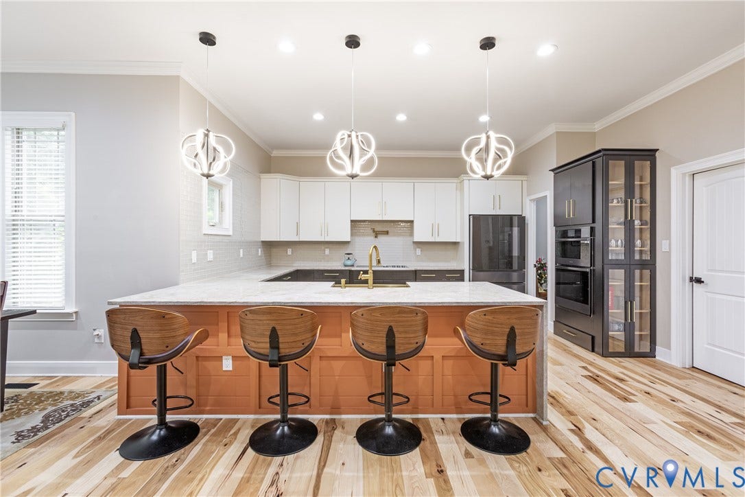 12554 Kain Road, Glen Allen, VA 23059 Kitchen featuring an expansive island with a light-toned countertop, dual-toned cabinetry, stainless steel appliances, and wood-finish flooring