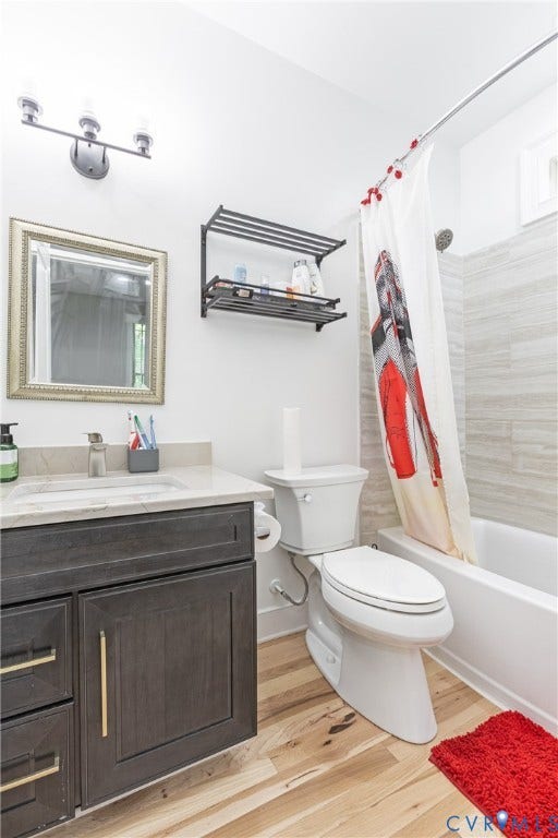 12554 Kain Road, Glen Allen, VA 23059 Contemporary bathroom featuring a dark vanity with brushed gold hardware, white quartz countertop, framed mirror with decorative trim, wall-mounted dual-fixture lighting, subway tile shower surround, and wood-finish flooring throughout