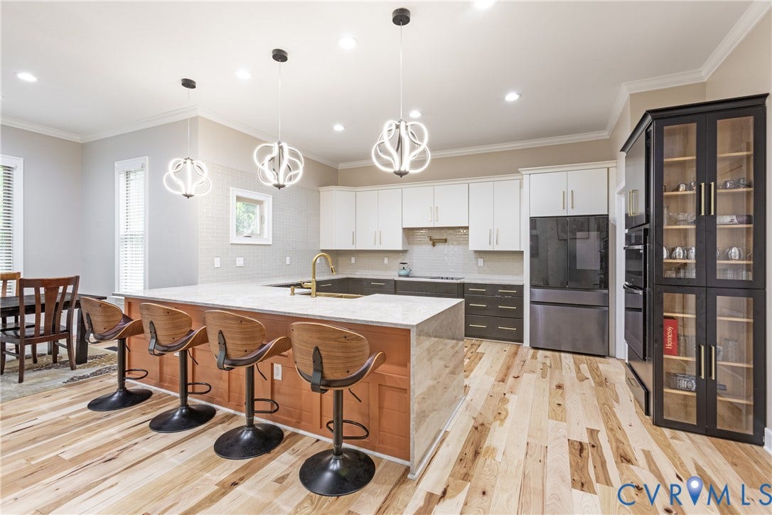 12554 Kain Road, Glen Allen, VA 23059 Open-concept kitchen with wood-finish flooring, a large island with seating, pendant lighting, and built-in display cabinetry