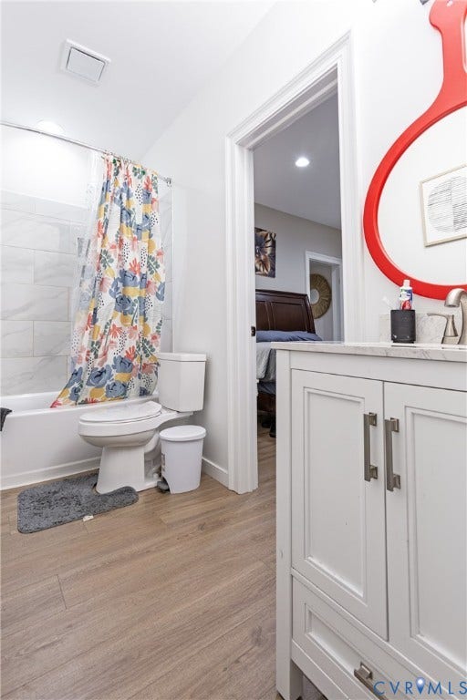 12554 Kain Road, Glen Allen, VA 23059 Spa-inspired bathroom featuring white shaker cabinetry with brushed metal hardware, wood-finish flooring, subway tile surround, and a coordinating floral shower curtain