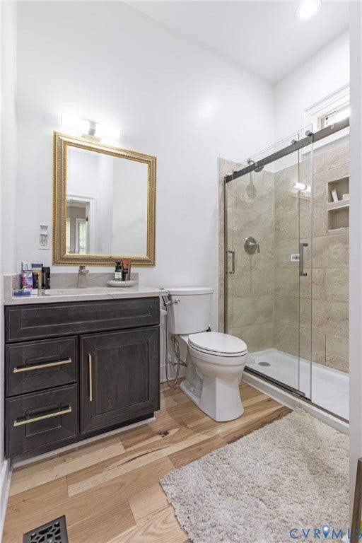 12554 Kain Road, Glen Allen, VA 23059 Spa-inspired primary bathroom showcasing a custom dark cabinetry vanity with brass hardware, framed mirror with brass detailing, and a spacious walk-in shower with frameless glass enclosure and tile surround