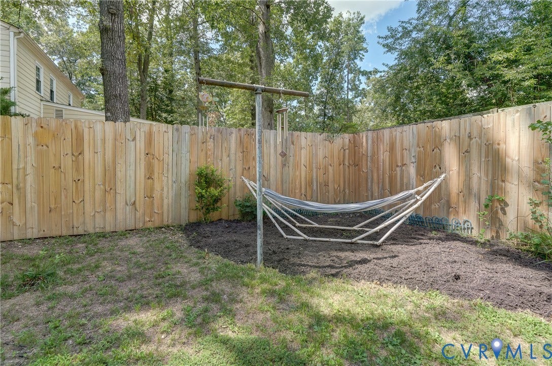Backyard featuring wood privacy fencing, established trees, and a mulched planting area