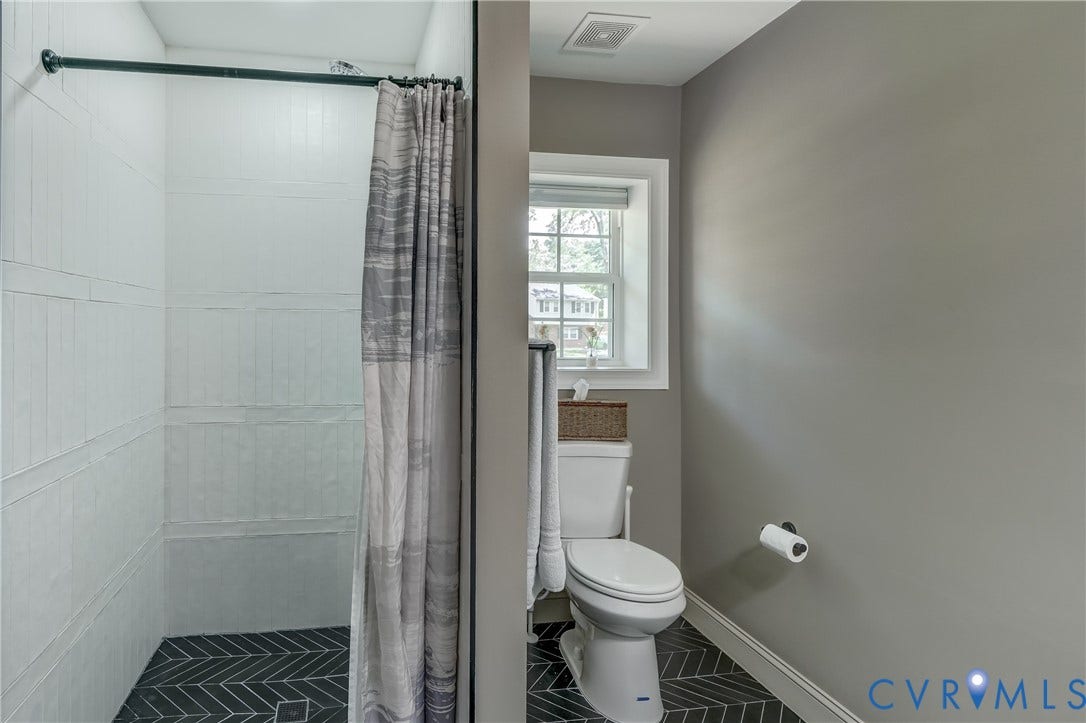 White subway tile shower with a herringbone floor