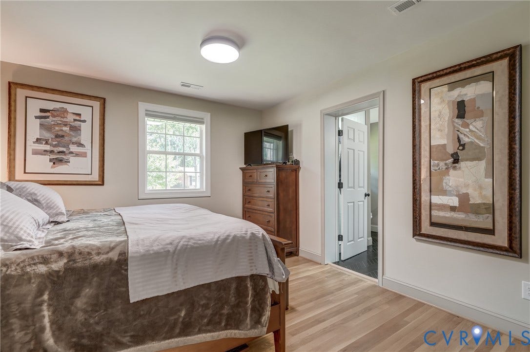 Light wood-finish flooring, a double-hung window, a white paneled door, and a flush-mount ceiling light