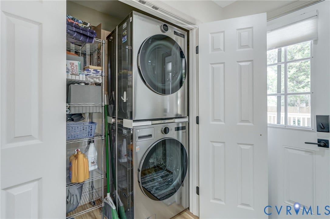 Dedicated laundry area featuring a stacked washer and dryer, adjacent to a storage shelving unit