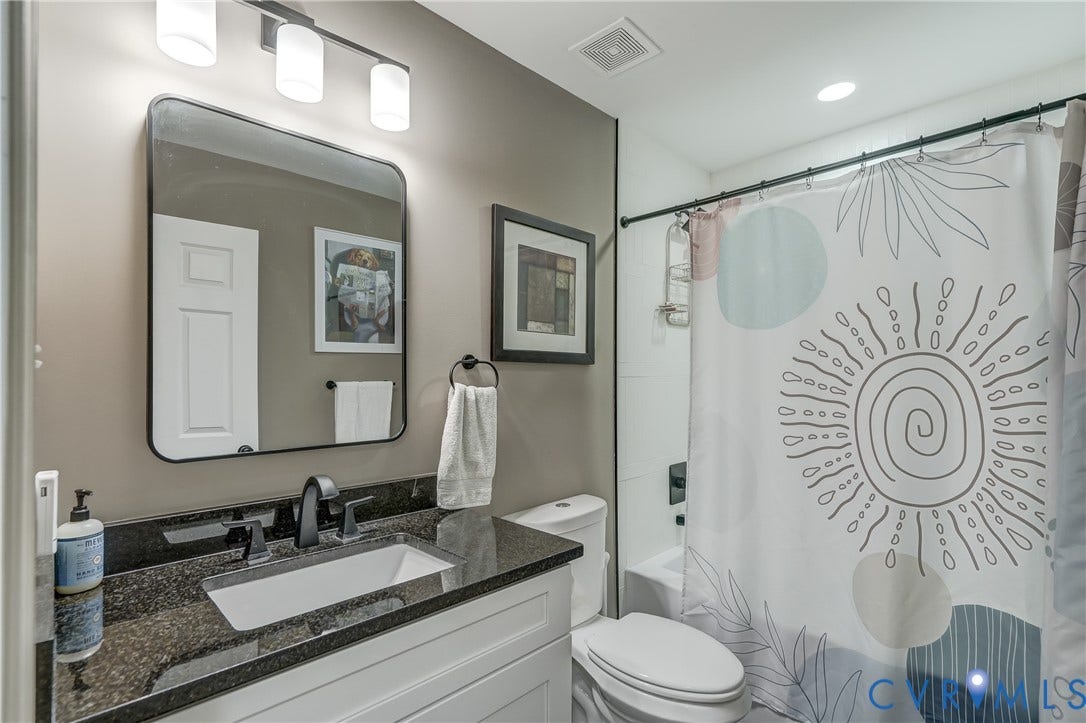 White vanity with dark stone countertop, undermount sink, and matte black faucet