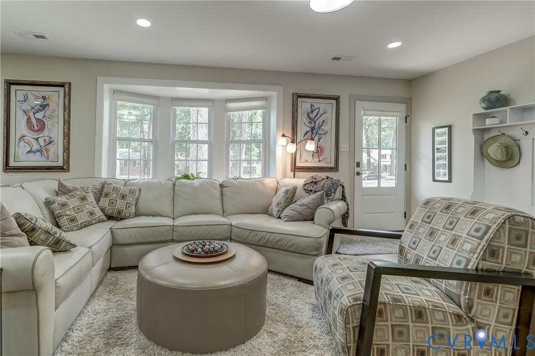 Bay window with multiple panes, recessed ceiling lighting, wall-mounted coat rack with shelving, white paneled door, and light-toned wall finishes