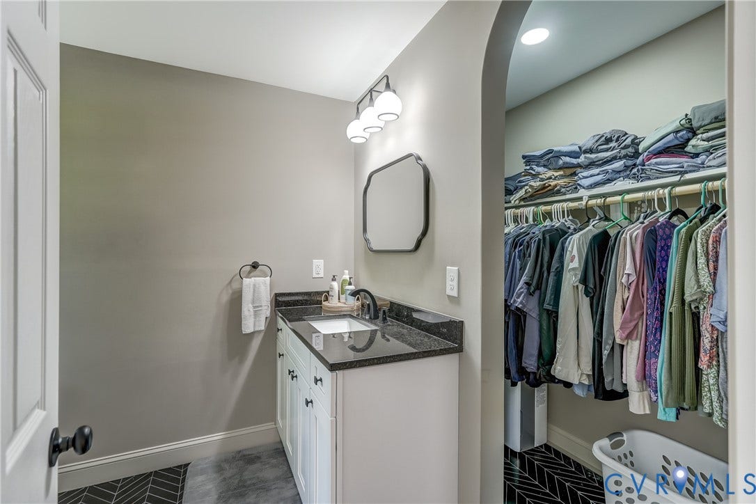 White vanity with dark countertop, rectangular undermount sink, and wall-mounted mirror
