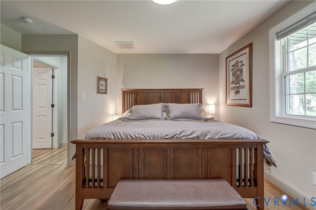 Light wood-finish flooring, two-panel interior doors, light neutral wall color, and a window with white trim