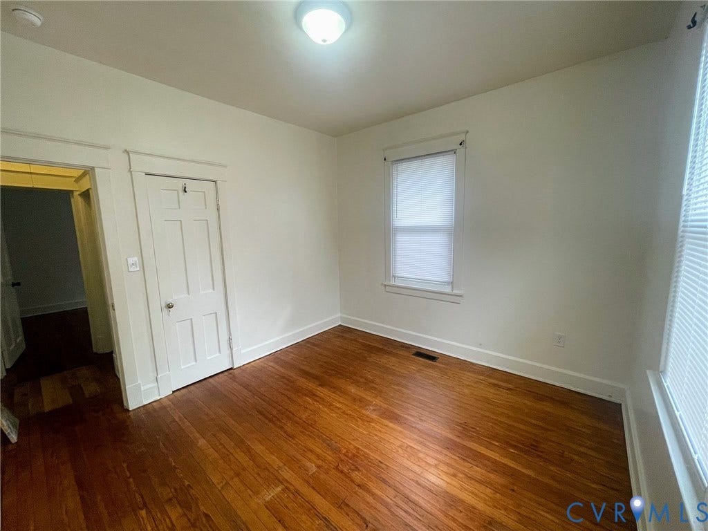 Room featuring wood-finish flooring, white walls, and a flush-mount ceiling light