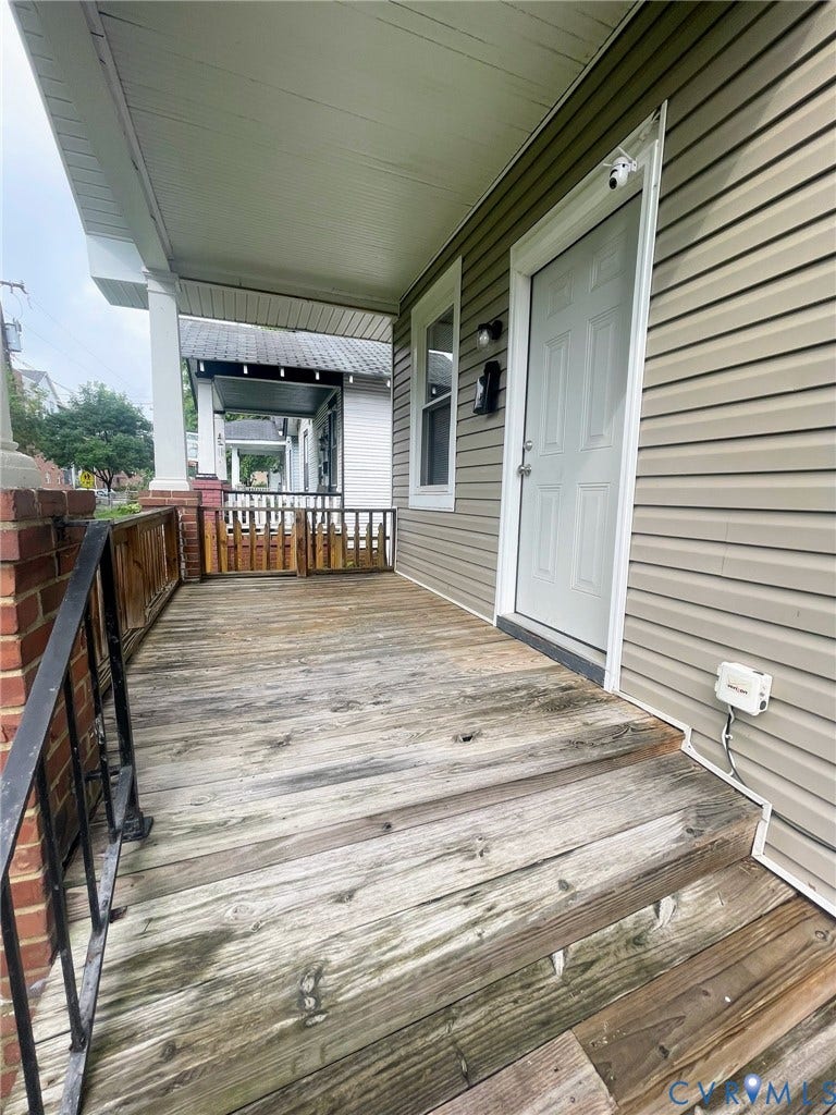 Covered front porch featuring wood plank decking and steps