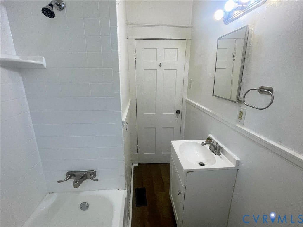 Bathroom featuring a white vanity with an integrated sink, polished chrome faucet, and a wall-mounted mirror