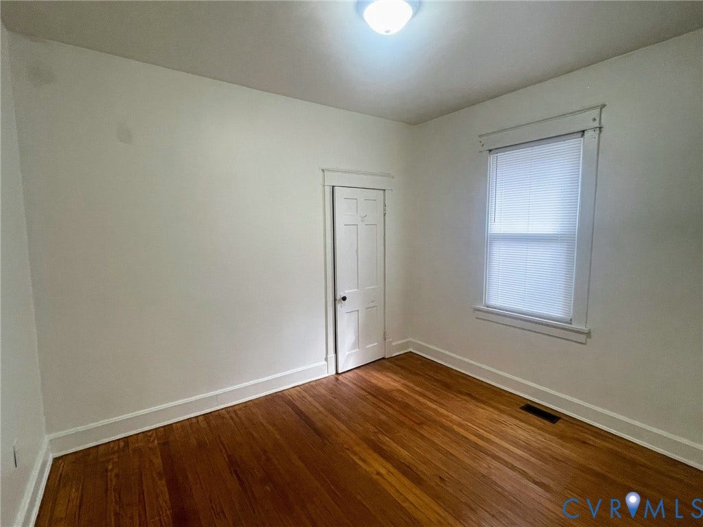 Room featuring rich wood-finish flooring and white baseboard trim