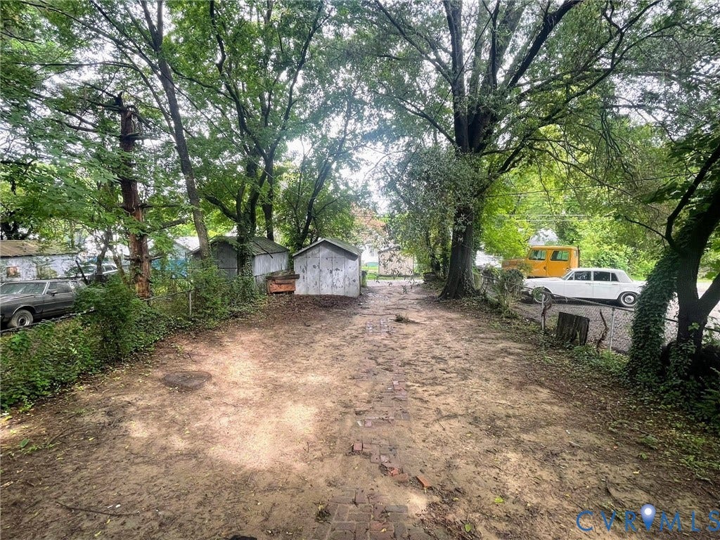Expansive dirt lot featuring mature trees providing ample shade