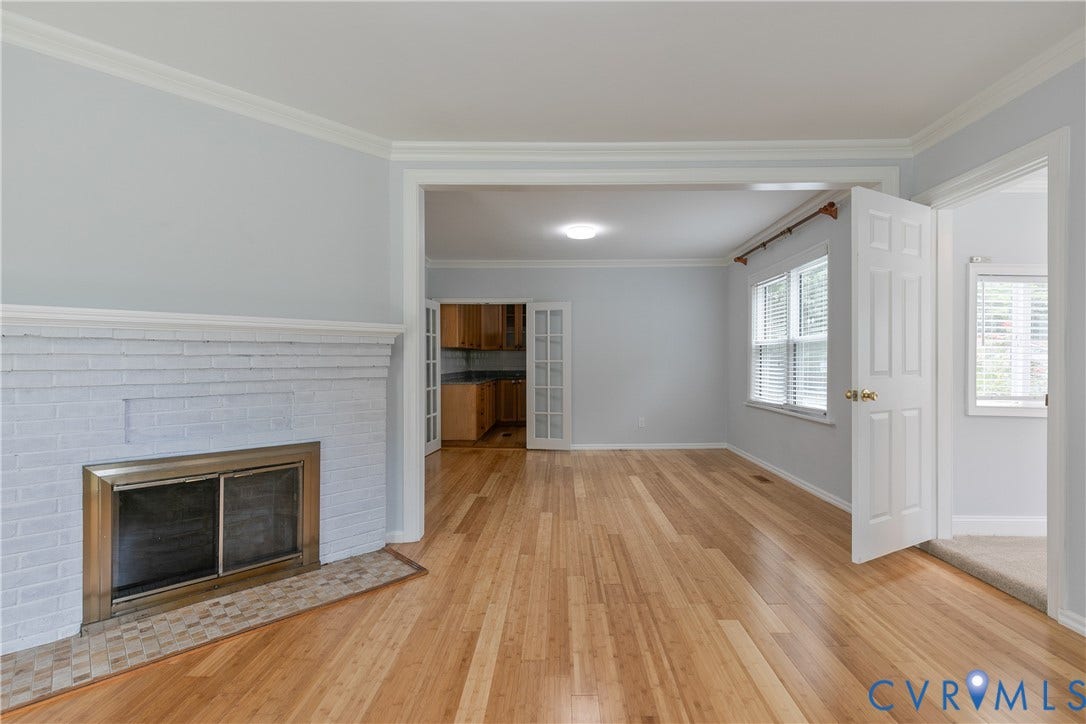 4809 Penick Road, Brookland, Henrico, VA 23228 Open-concept living space featuring hardwood flooring, a white-painted brick fireplace with a brass firebox, and crown molding