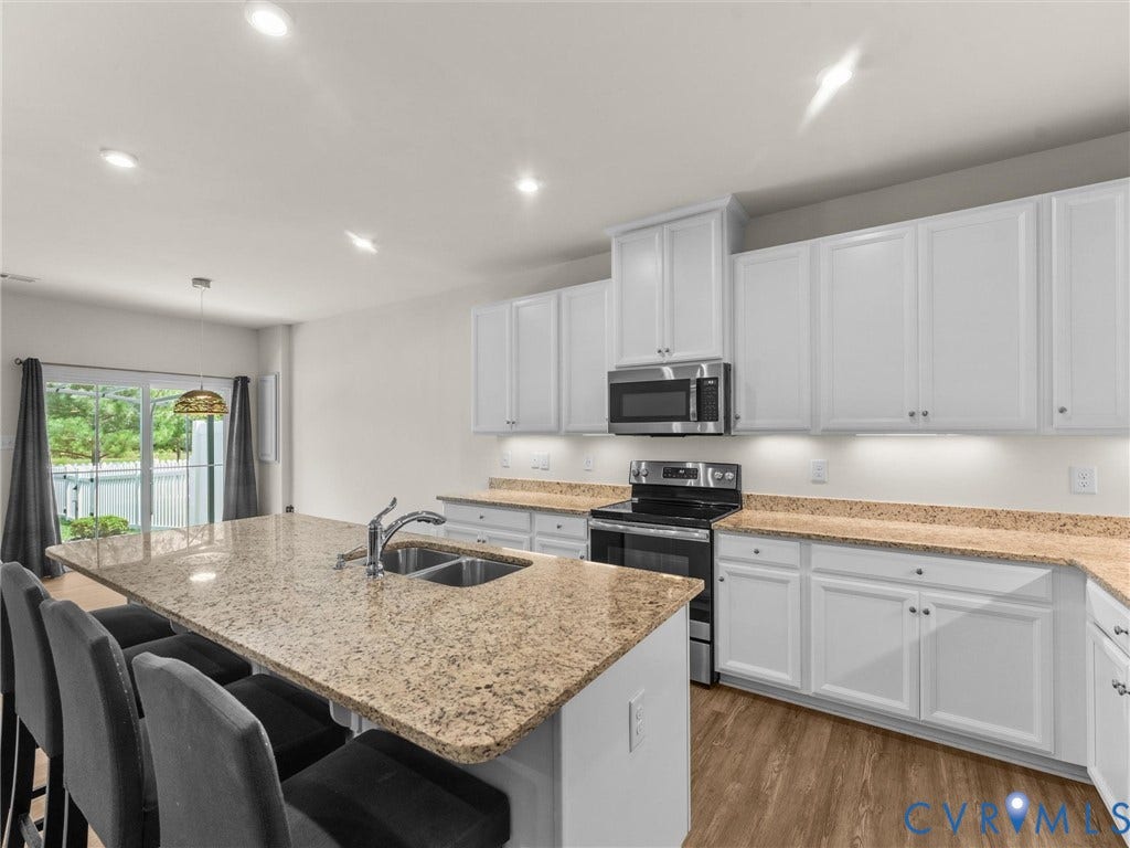 12601 Prestonfield Drive, Blalock, Chesterfield, VA 23836 Kitchen island with a double basin sink, light-toned countertops, white cabinetry, stainless steel appliances, and wood-finish flooring