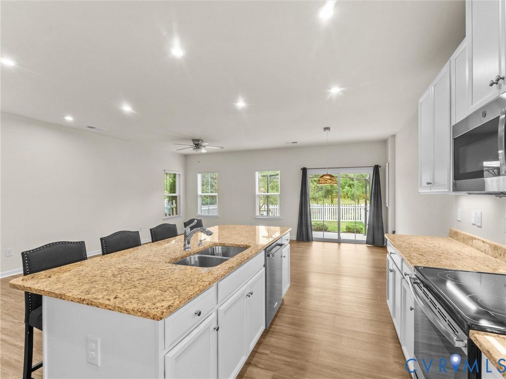 12601 Prestonfield Drive, Blalock, Chesterfield, VA 23836 Kitchen featuring a large island with a double basin sink, white cabinetry, integrated stainless steel appliances, and wood-finish flooring