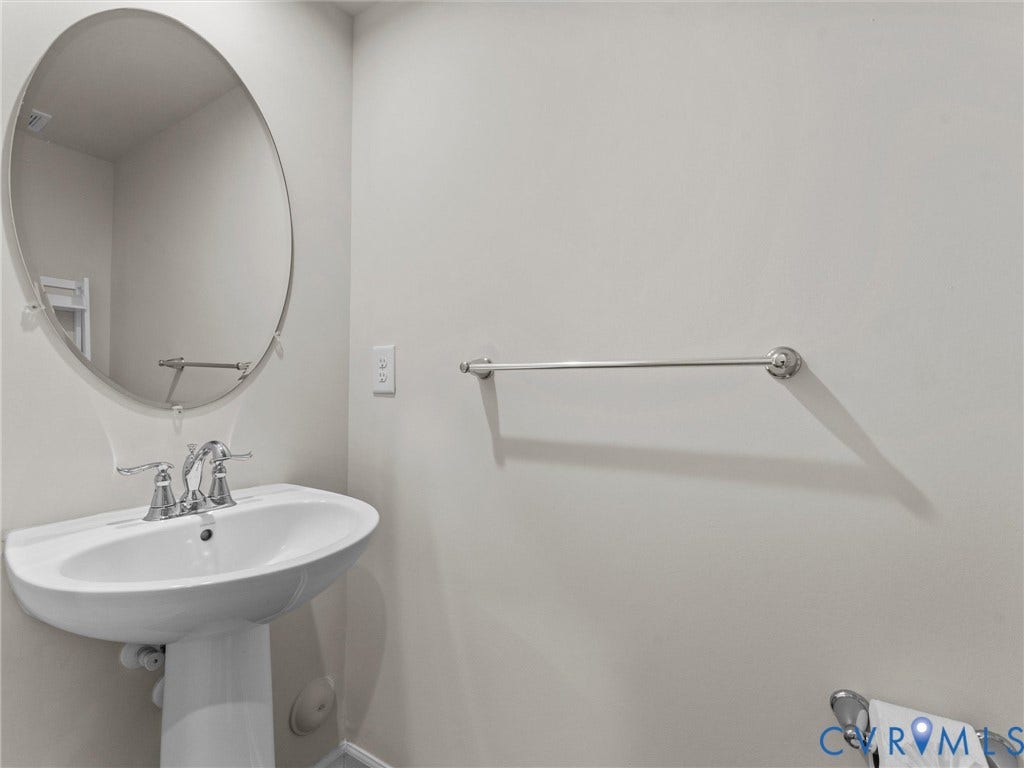 12601 Prestonfield Drive, Blalock, Chesterfield, VA 23836 Pedestal sink with chrome fixtures, oval wall-mounted mirror, and wall-mounted towel bars