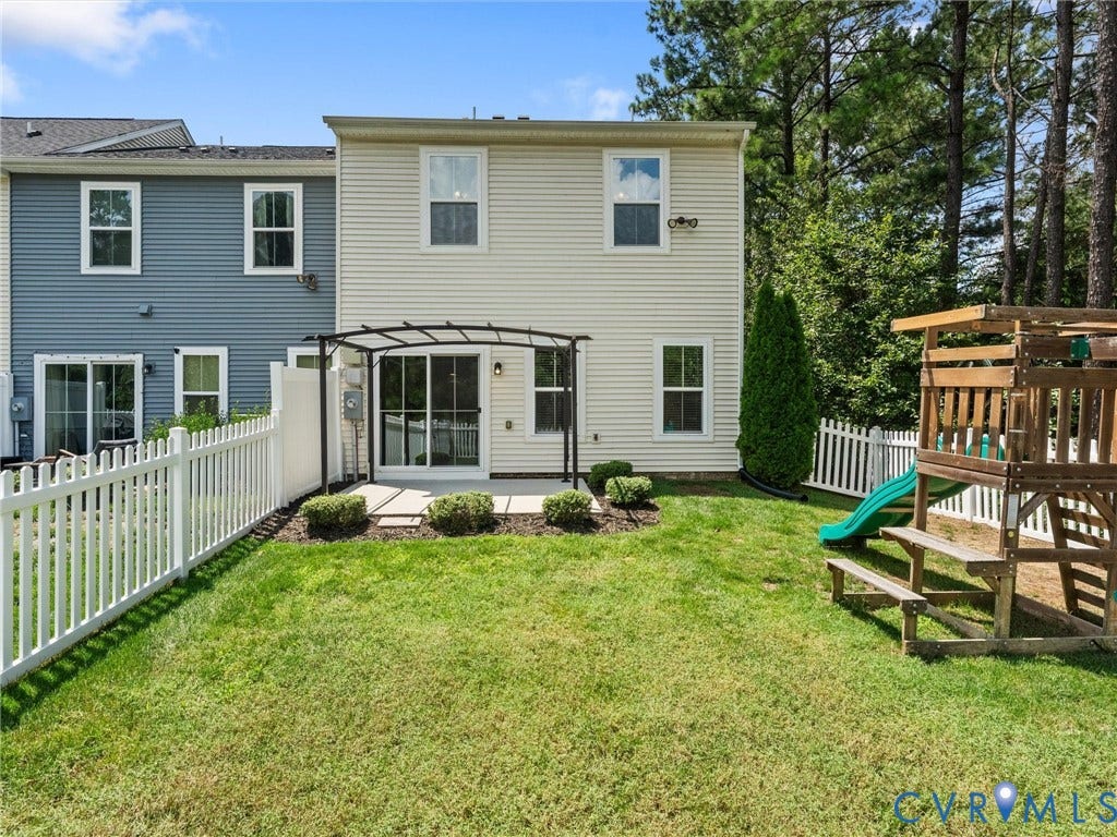 12601 Prestonfield Drive, Blalock, Chesterfield, VA 23836 Backyard featuring a white picket fence, a patio with square pavers, a black metal pergola, and mature trees beyond the property line
