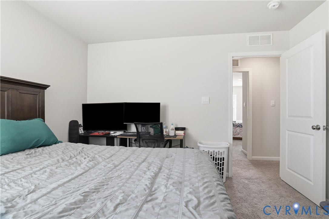 Carpeted room with light neutral wall paint and a dark wood-finish headboard
