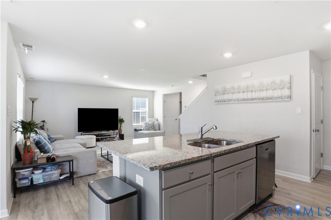 Kitchen island featuring a stainless steel sink with a high-arc faucet, integrated dishwasher, and granite countertop