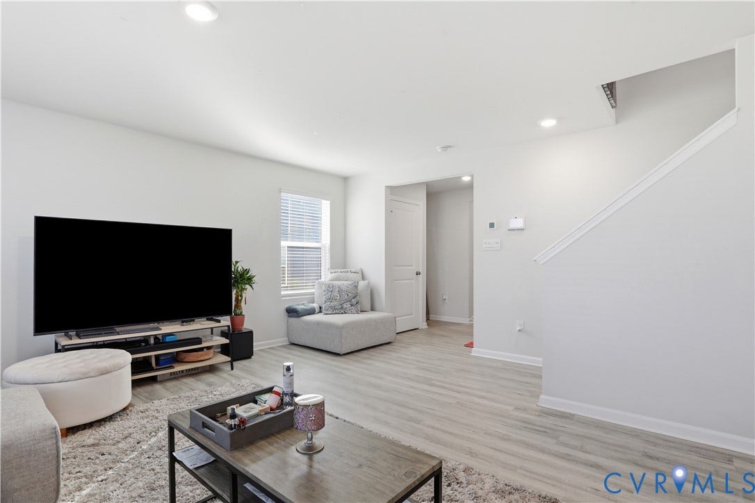 Living area featuring light wood-finish flooring, recessed lighting, and a window with blinds