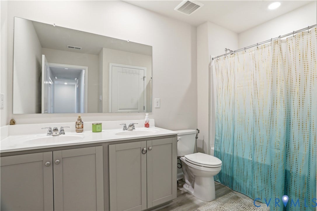 Dual sink vanity with light gray cabinetry and white countertops