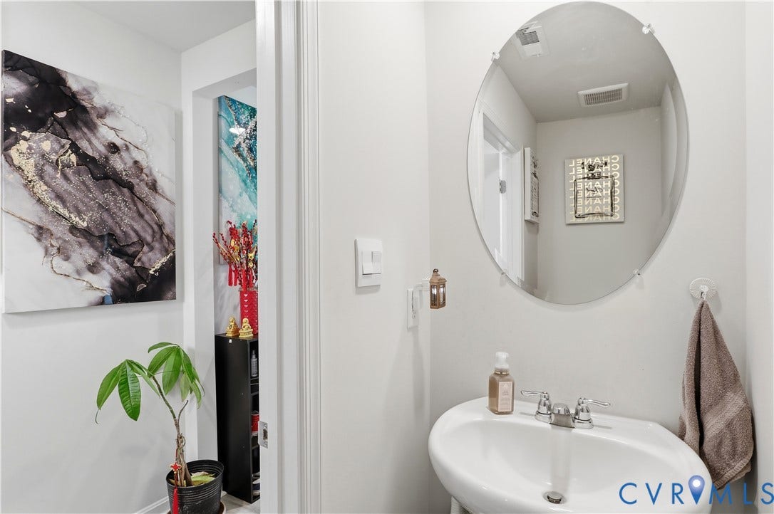 Pedestal sink with chrome faucet, complemented by an oval frameless mirror