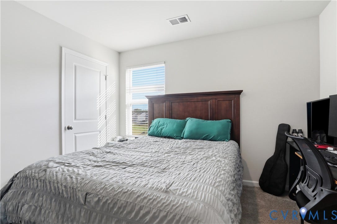 Bedroom featuring neutral wall color, carpet flooring, a white paneled door, and a window with horizontal blinds