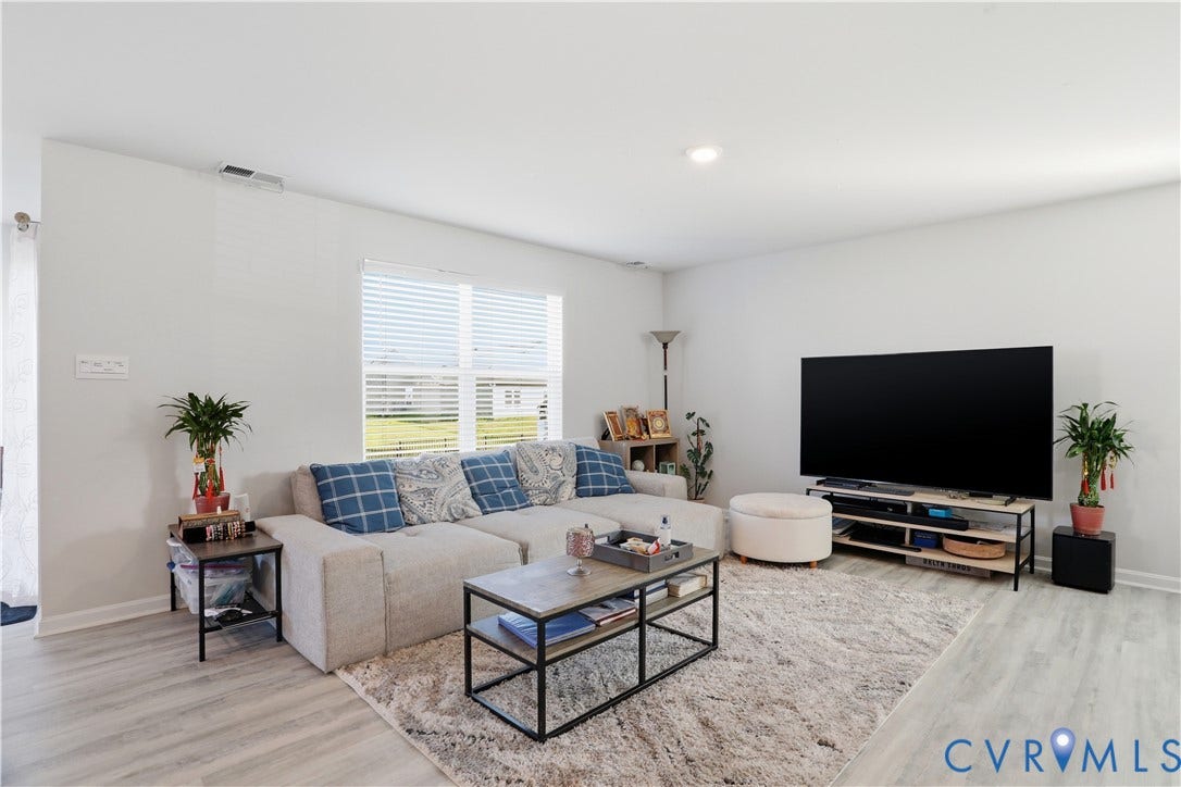 Spacious room featuring light-toned flooring, white walls, and a large window with horizontal blinds