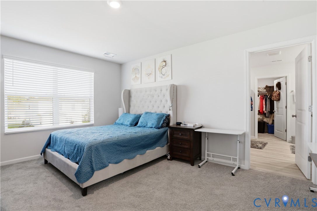 Carpeted room with a large window featuring horizontal blinds