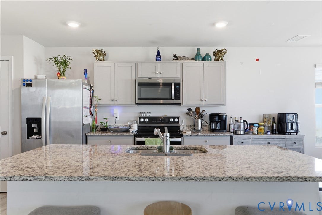 Kitchen featuring a large island with an undermount sink, light-toned cabinetry, stainless steel appliances, and recessed lighting