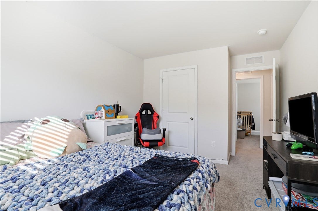 Carpeted interior room featuring light gray wall paint, white trim, and a white two-panel door