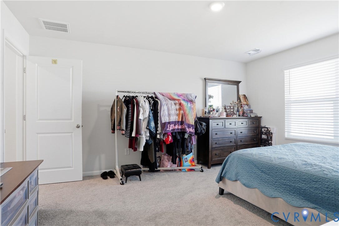 Carpeted room featuring a white two-panel interior door, a single window with horizontal blinds, and a ceiling-mounted light fixture