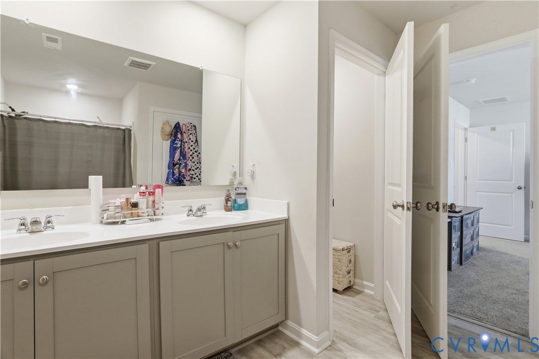 Bathroom featuring a double vanity with light gray cabinetry, white countertops, and chrome fixtures