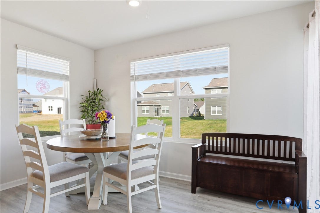 Bright dining area featuring light wood-finish flooring and white painted walls