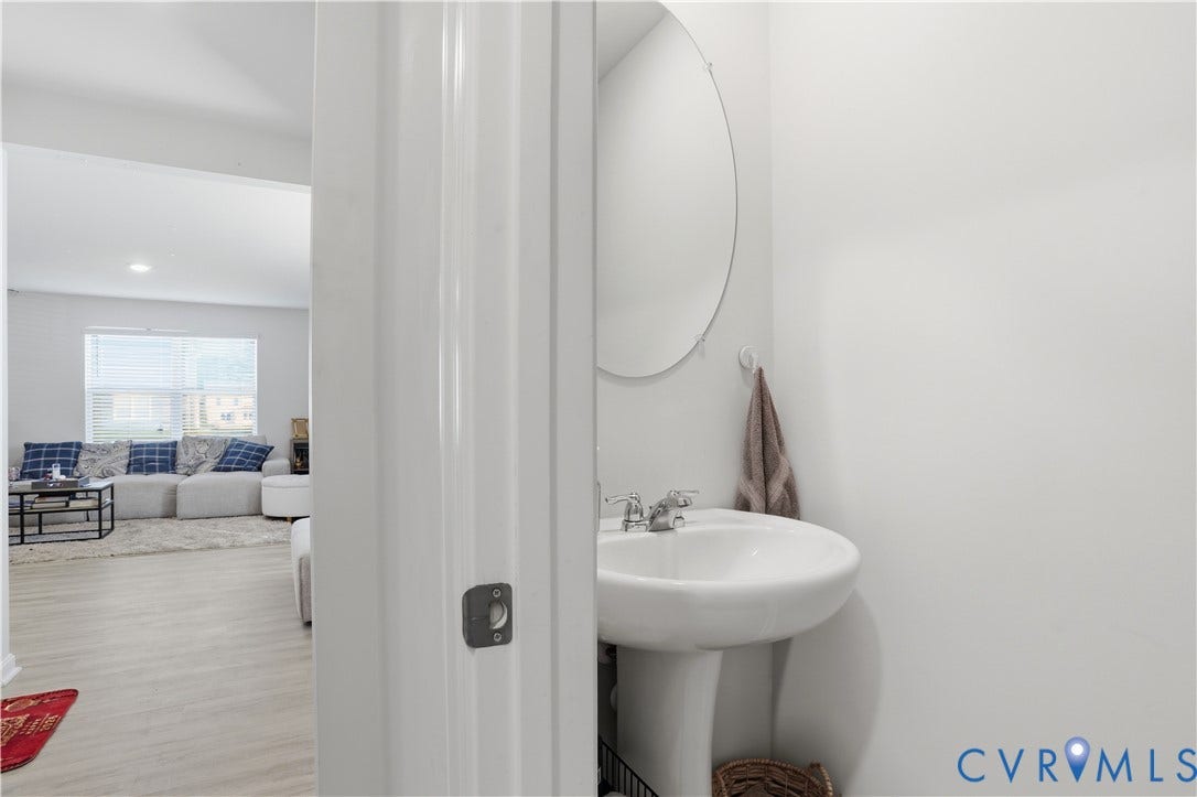 Pedestal sink with chrome fixtures and a round wall-mounted mirror