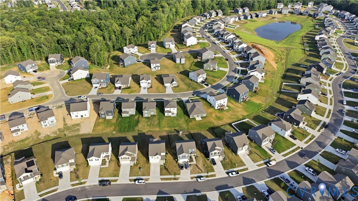 Residential development featuring a central pond, curvilinear streets, and a tree-lined perimeter
