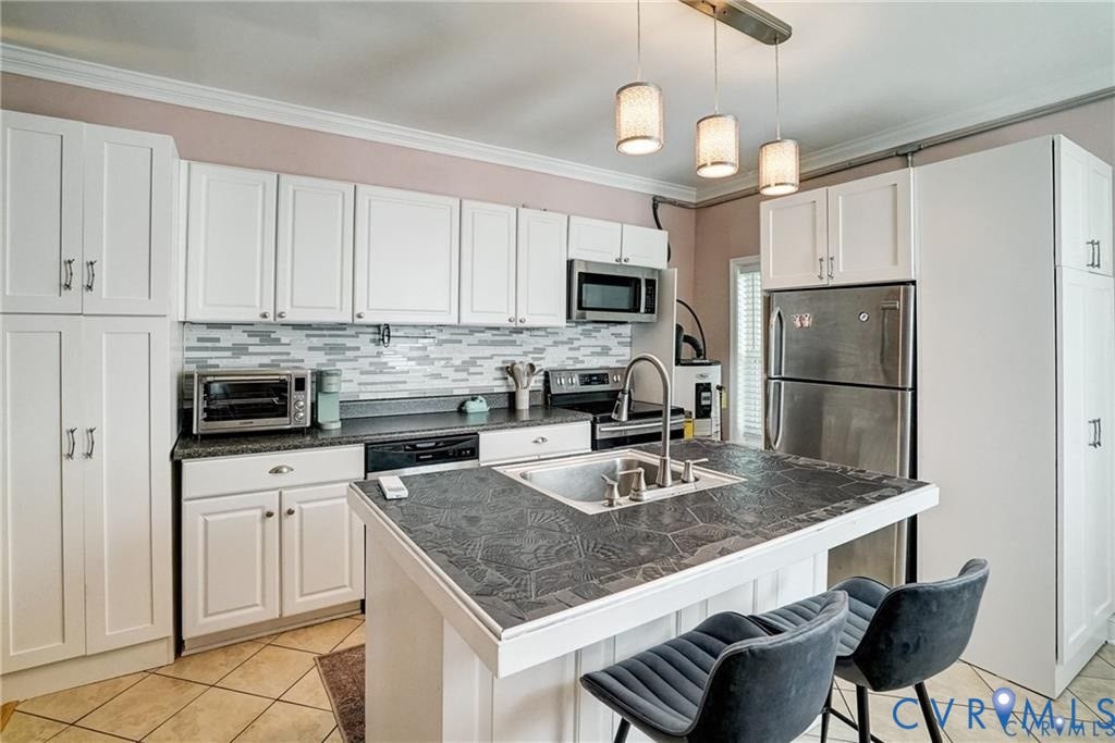 1410 W Clay Street, Richmond, VA 23220 Kitchen with dark countertops, light tile patterned floors, a kitchen breakfast bar, white cabinetry, and ornamental molding