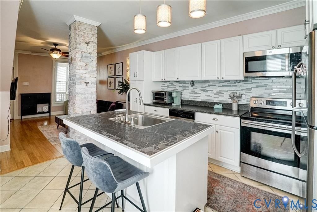 1410 W Clay Street, Richmond, VA 23220 Kitchen with stainless steel appliances, a kitchen bar, light tile patterned flooring, white cabinets, and crown molding