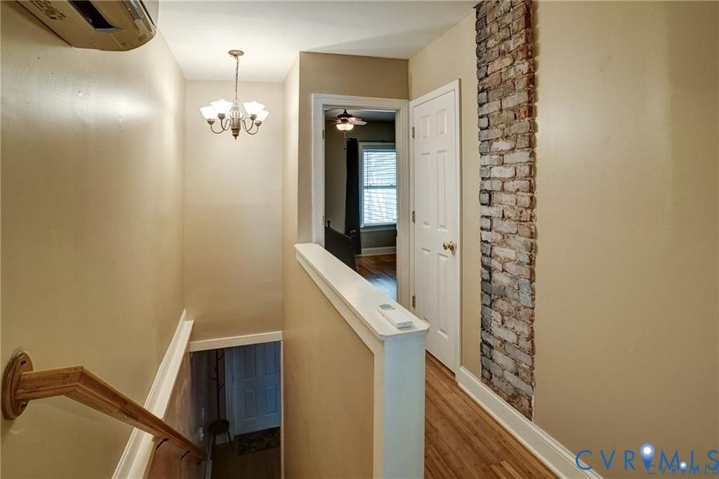 1410 W Clay Street, Richmond, VA 23220 Corridor with wood finished floors, an upstairs landing, an AC wall unit, and a chandelier