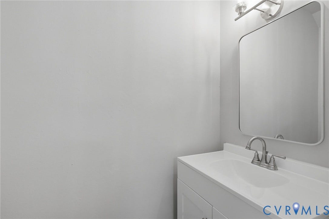 3218 Hunters Mill Court, Henrico, VA 23223 White vanity with an integrated sink, brushed nickel faucet, and a wall-mounted rectangular mirror