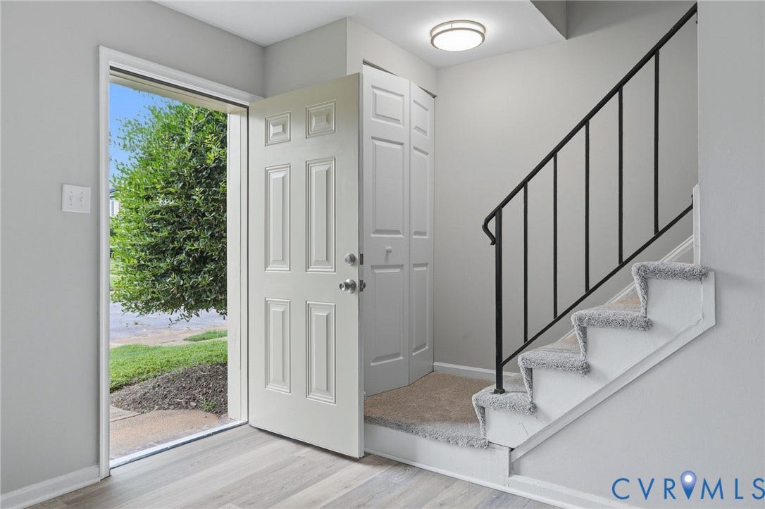 3218 Hunters Mill Court, Henrico, VA 23223 Entryway featuring wood-finish flooring, a white paneled door, and a staircase with carpeted treads and a black metal handrail