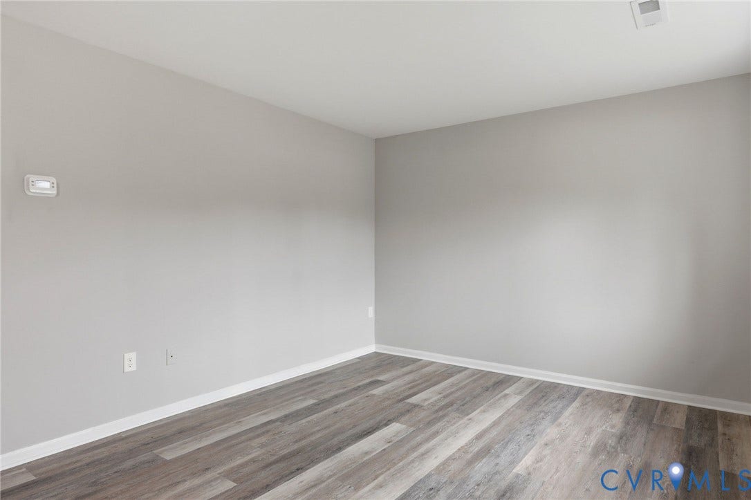 3218 Hunters Mill Court, Henrico, VA 23223 Spacious room featuring wood-finish flooring, light grey painted walls, white baseboards, and a ceiling-mounted HVAC vent