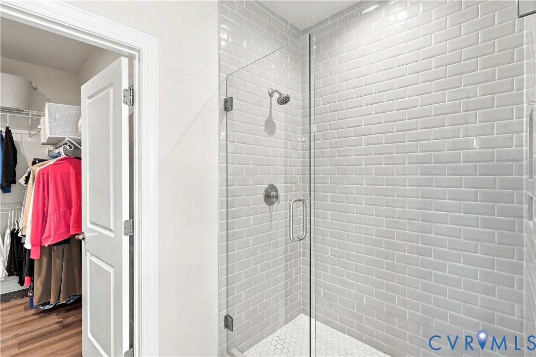 7437 Aldeby Street, Glen Allen, VA 23059 Glass-enclosed shower with subway tile walls, a rain showerhead, brushed metal hardware, and hexagon tile flooring