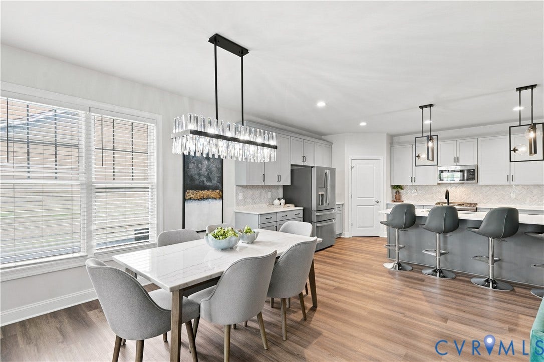 7437 Aldeby Street, Glen Allen, VA 23059 Open-concept kitchen and dining area featuring wood-finish flooring, white cabinetry, stainless steel appliances, and a kitchen island with pendant lighting